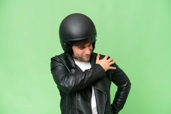 若いですCaucasian男でオートバイのヘルメットで隔離された緑のクロマの背景に痛みに苦しんで肩の努力をした — ストック写真