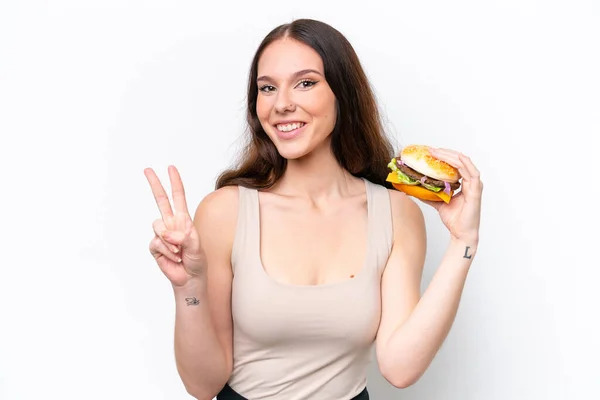 Young Caucasian Woman Holding Burger Isolated White Background Smiling Showing — Zdjęcie stockowe
