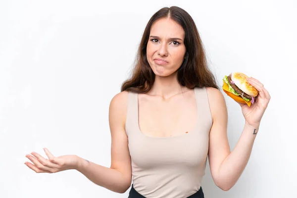 Młoda Kaukaska Kobieta Trzyma Hamburgera Odizolowanego Białym Tle Robiąc Wątpliwy — Zdjęcie stockowe