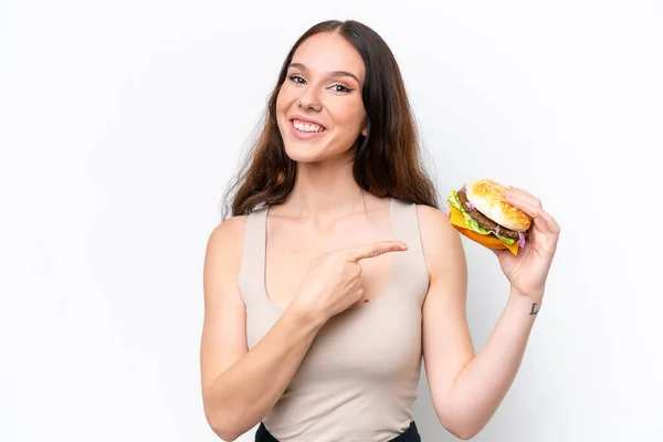 Młoda Kaukaska Kobieta Trzymając Hamburgera Białym Tle Wskazując — Zdjęcie stockowe