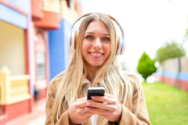 Молодая Красивая Блондинка Открытом Воздухе Слушает Музыку Мобильного Телефона Смотрит — стоковое фото