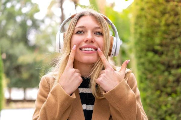 Νεαρή Όμορφη Ξανθιά Γυναίκα Ακούει Μουσική Ακουστικά Εξωτερικούς Χώρους Χαμογελώντας — Φωτογραφία Αρχείου
