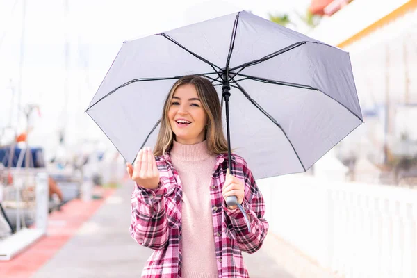 年轻漂亮的罗马尼亚女人在户外拿着一把雨伞 邀她来 很高兴你来了 — 图库照片