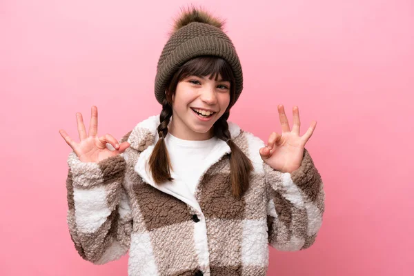 一个穿着冬季夹克的高加索小女孩 背景为粉色 手指头上有一个可控的标志 — 图库照片