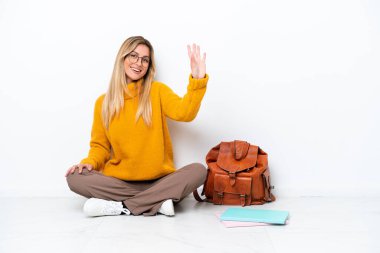 Bir katta oturan Uruguaylı öğrenci kadın beyaz arka planda izole edilmiş mutlu bir ifadeyle selamlıyor.