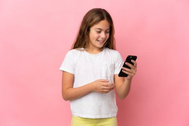 İzole edilmiş pembe arkaplan üzerindeki çocuk cep telefonuyla bir mesaj veya e- posta gönderiyor