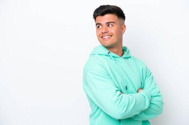 Beyaz arka planda soyutlanmış beyaz tenli yakışıklı bir adam yan tarafa bakıyor ve gülümsüyor.