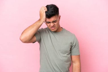 Pembe arka planda yalnız ve başı ağrıyan beyaz, yakışıklı genç bir adam.