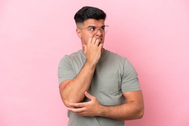 Pembe arka planda izole edilmiş beyaz tenli yakışıklı bir adam biraz gergin.