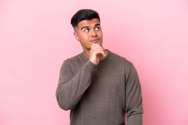 Beyaz tenli yakışıklı adam pembe arka planda izole edilmiş ve yukarı bakıyor.