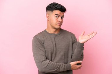 Pembe arka planda izole edilmiş beyaz, yakışıklı genç bir adam. Şüpheleri var.