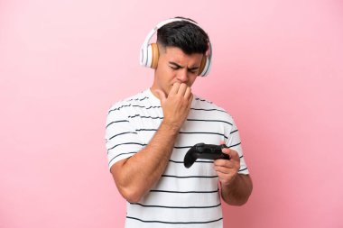 Pembe arka planda izole edilmiş bir video oyunu kontrolörüyle oynayan yakışıklı genç adamın şüpheleri var.