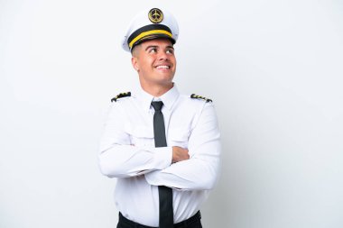 Uçak pilotu beyaz arka planda izole edilmiş beyaz bir adam gülümserken yukarı bakıyor.