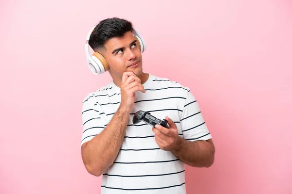 Νεαρός Όμορφος Άντρας Παίζει Ένα Χειριστήριο Βιντεοπαιχνιδιών Απομονωμένο Ροζ Φόντο — Φωτογραφία Αρχείου