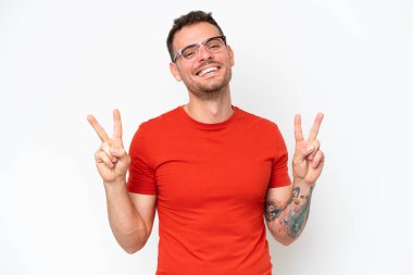 Beyaz arka planda izole edilmiş beyaz, beyaz, yakışıklı bir genç zafer işareti gösteriyor.