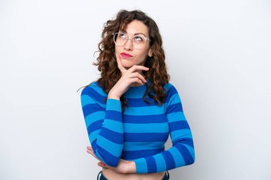 Beyaz arka planda izole edilmiş genç beyaz kadın yukarı bakarken şüpheleri var.