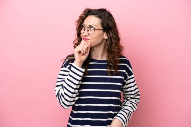 Genç beyaz kadın pembe arka planda izole edilmiş ve yukarı bakıyor.