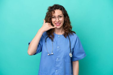 Young nurse caucasian woman isolated on blue background making phone gesture. Call me back sign