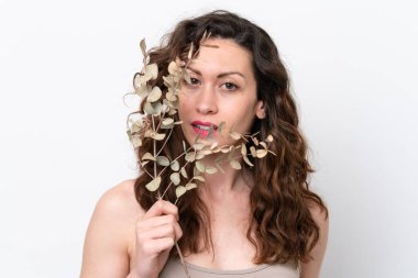 Beyaz arka planda, elinde okaliptüs dalı tutan beyaz tenli bir kadın. Portreyi kapat