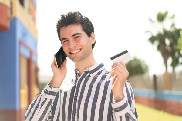 Młody Przystojny Mężczyzna Prowadzi Rozmowę Telefonem Komórkowym Trzyma Kartę Kredytową — Zdjęcie stockowe