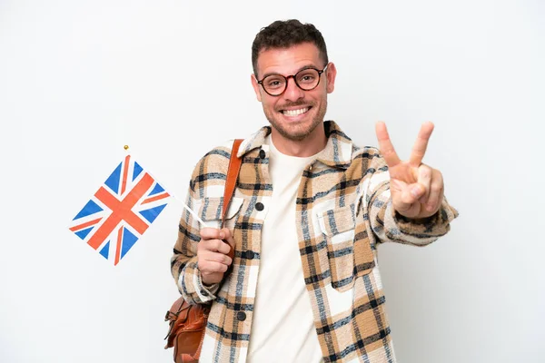 Молодой Латиноамериканец Флагом Великобритании Белом Фоне Улыбается Показывает Знак Победы — стоковое фото