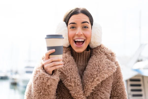 Mladá Žena Nosí Zimní Manžety Drží Odnést Kávu Venku Překvapením — Stock fotografie