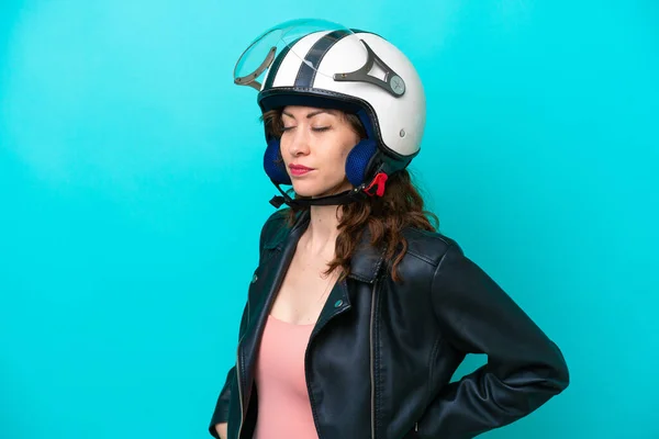 若いですCaucasian女性とともにオートバイヘルメット隔離された上に青の背景苦しみから腰痛のための努力をした — ストック写真