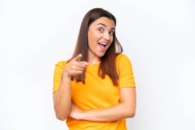 Beyaz arka planda izole edilmiş genç beyaz kadın şaşırmış ve ön tarafı işaret ediyor.