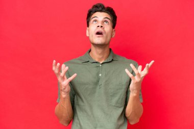 Kızıl arka planda izole edilmiş beyaz, yakışıklı genç bir adam bunalımda.