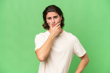 Kafkasyalı genç adam yeşil krom arka planda izole edilmiş. Şüpheleri var.