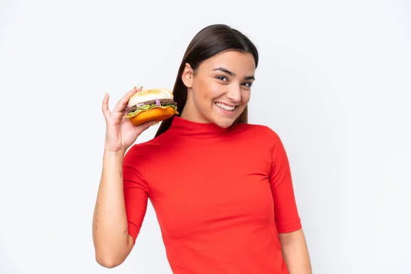 Młoda Kaukaska Kobieta Trzyma Hamburgera Izolowane Białym Tle Uśmiechając Się — Zdjęcie stockowe