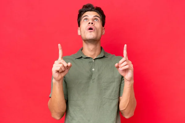 Young Caucasian Handsome Man Isolated Red Background Surprised Pointing — Stock Photo, Image