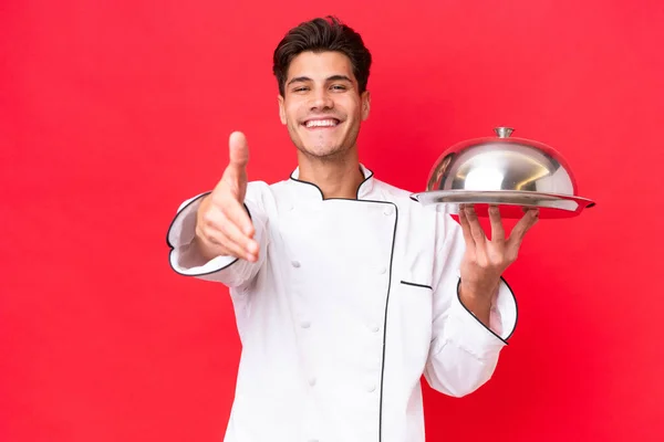 Jeune Chef Caucasien Homme Tenant Plateau Isolé Sur Fond Rouge — Photo