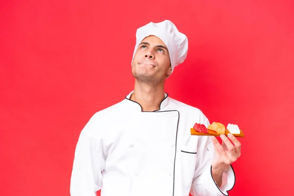 Ung Kaukasisk Kock Man Som Håller Sashimi Isolerad Röd Bakgrund — Stockfoto