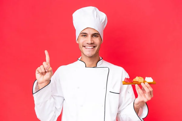 Joven Chef Caucásico Hombre Sosteniendo Sashimi Aislado Sobre Fondo Rojo — Foto de Stock