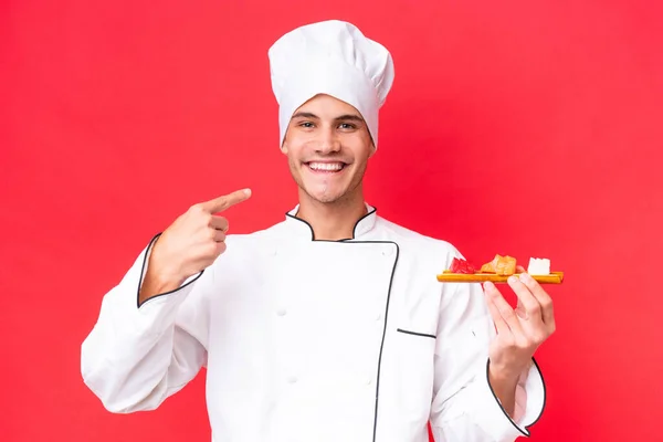 Jeune Chef Caucasien Homme Tenant Sashimi Isolé Sur Fond Rouge — Photo