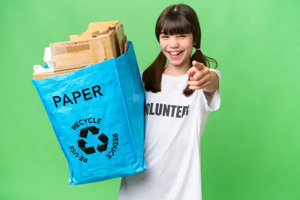 小さな白人の女の子を保持していますリサイクルバッグフル紙でリサイクルするために隔離された背景点指上であなたに自信を持って式 — ストック写真