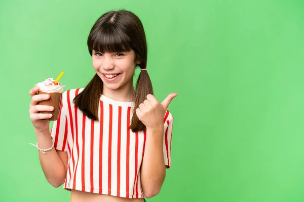 stock image Young man with chocolat milkshake over isolated background pointing to the side to present a product