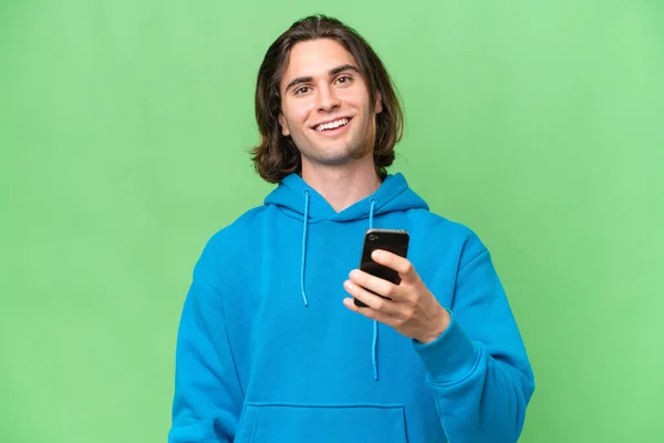 携帯電話を使用して緑のクロマの背景に隔離された若いハンサムな男 — ストック写真