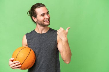 Tecrit edilmiş arka planda genç basketbolcu bir ürünü sunmak için kenarı işaret ediyor.