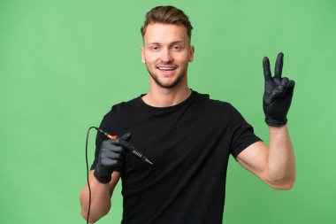 Dövmeci beyaz adam izole edilmiş arka planda gülümsüyor ve zafer işareti gösteriyor.