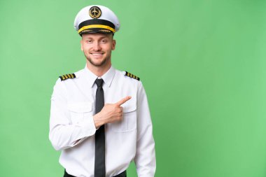Uçak pilotu izole edilmiş arka planda bir ürünü sunmak için kenarı işaret ediyor.