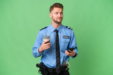 Arka planda izole edilmiş genç bir polis. Elinde kahve ve bir şeyler düşünürken cep telefonu var.
