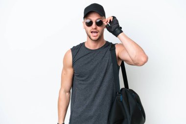 Spor çantalı genç sarışın, beyaz tenli, gözlüklü ve şaşırmış.