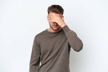 Beyaz arka planda başı ağrıyan genç, sarışın, beyaz bir adam.