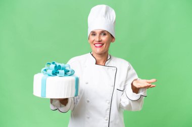 Yüzünde şok ifadesi olan, izole edilmiş arka planda büyük bir pastası olan orta yaşlı beyaz bir kadın.