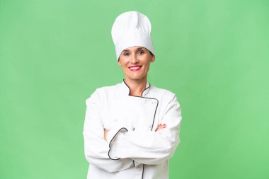 Orta yaşlı aşçı kadın, izole edilmiş arka planda kollarını ön cephede çapraz tutuyor.