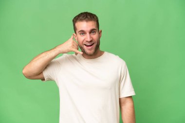 Yeşil krom arka planda izole edilmiş yakışıklı beyaz bir adam telefon jesti yapıyor. Bana geri dönüş işareti ver.