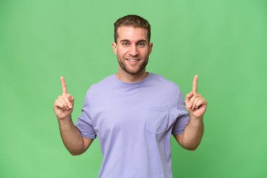 Yeşil krom arka planda izole edilmiş yakışıklı beyaz adam harika bir fikre işaret ediyor.