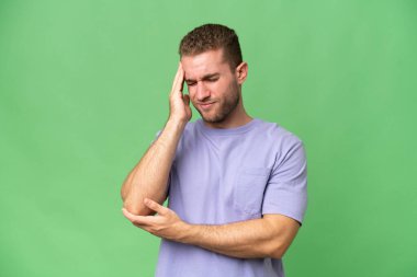 Genç, yakışıklı, beyaz adam yeşil krom arka planda izole edilmiş, baş ağrısı var.